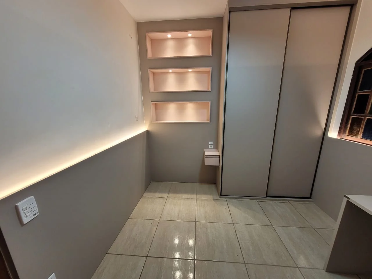Dormitório planejado com roupeiro e nichos iluminados